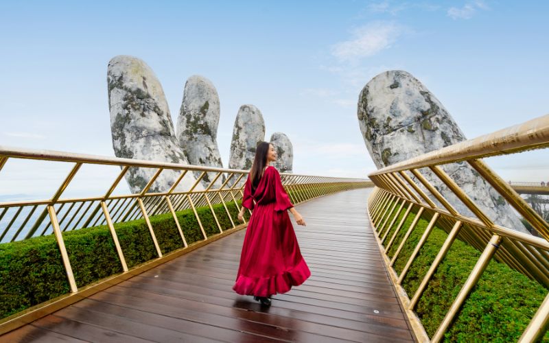 Young woman traveler in red dress enjoying at Golden Bridge in Bana hills, Danang Vietnam