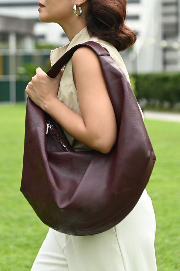 A woman wears a burgundy hobo bag